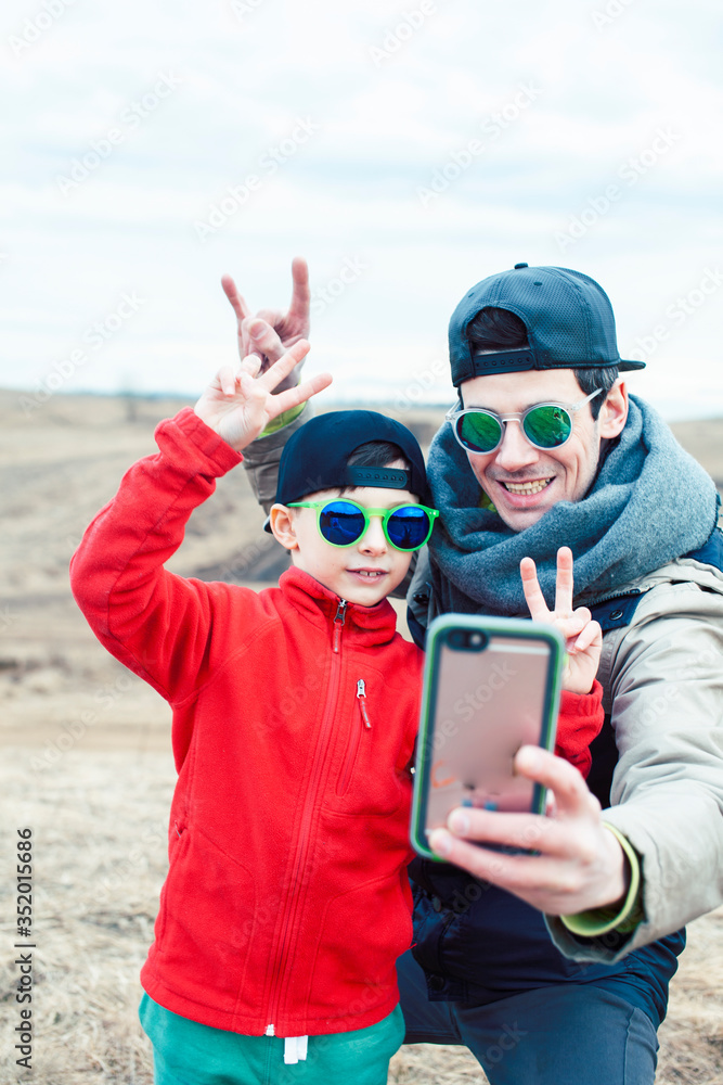 young father with his son having fun outside in spring field, happy family smiling, lifestyle people making selfie wearing sunglasses young father with his son having fun outside in spring field, happy family smiling, lifestyle people making selfie wearing sunglasses