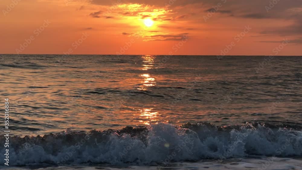 Sunrise over the calm sea, blurred reflected.  Yellow sun rises above sea, solar path on water. Sunlight and sun ray over sea reflect on water surface. Golden light, orange and gold blue sky, sea pano