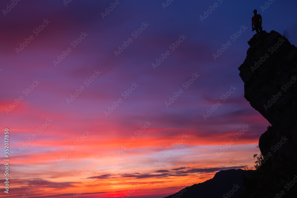 Silhouette d’un photographe au,sommet d’une montagne avec un magnifique coucher de soleil en arrière plan 