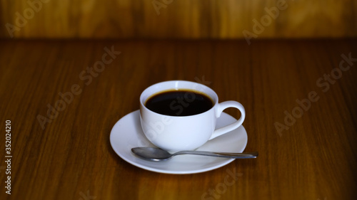 White small cup with saucer and cooled coffee