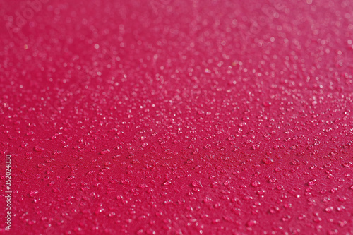 Close-up sectional view with selected focus on water drops on the red fabric of an umbrella after some drizzle