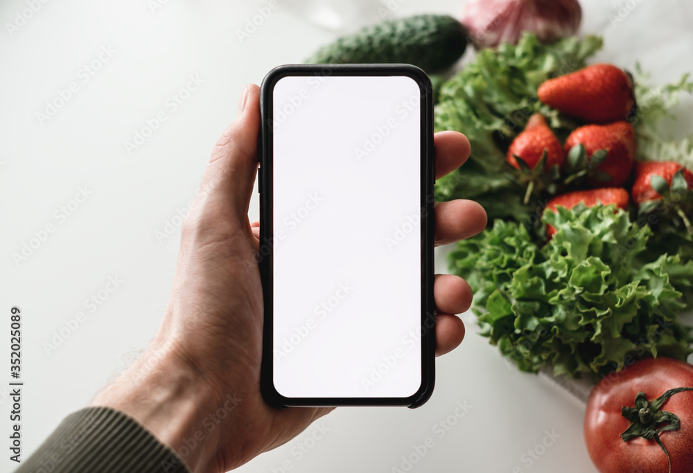 Hand hold the smartphone with white screen, mock up. Online food market concept.