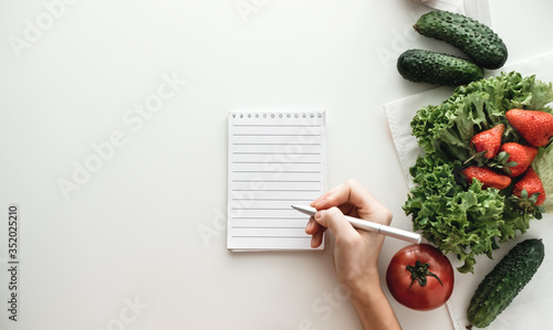 Woman makes notes in a notebook, food shopping list or writing recipes. Mock up. Flat lay with copy space. photo
