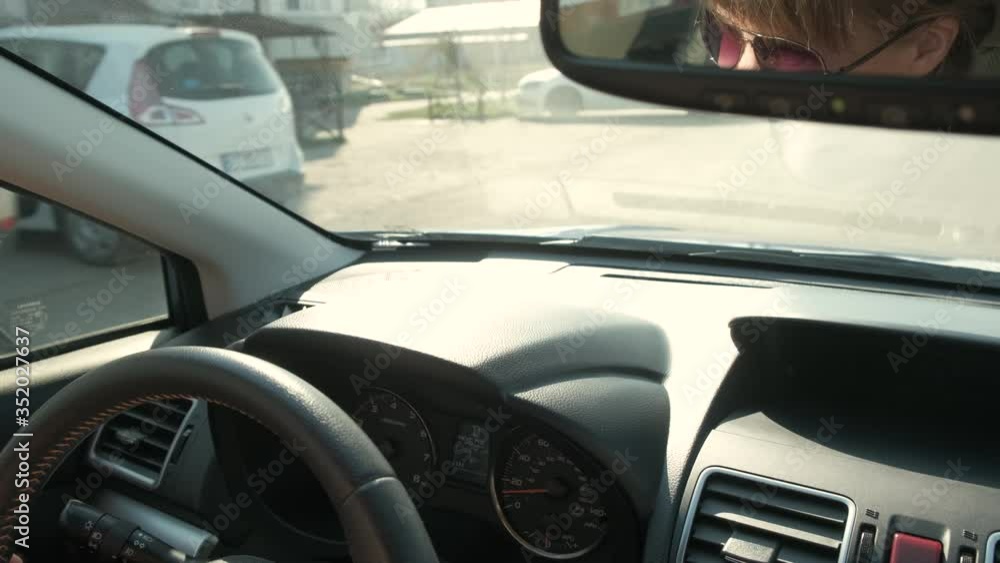Close up view of woman hands holding steering wheel driving a car on city street on sunny day. Close up view of woman hands holding steering wheel driving a car on city street on sunny day.