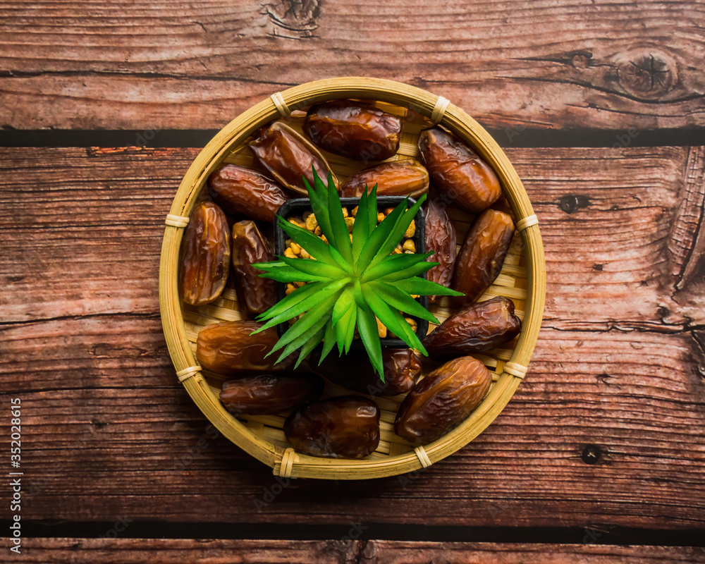 Dates or kurma on a wooden table with flower pot, the favorite food of the holy ramadhan month. Dates or kurma on a wooden table with flower pot, the favorite food of the holy ramadhan month.