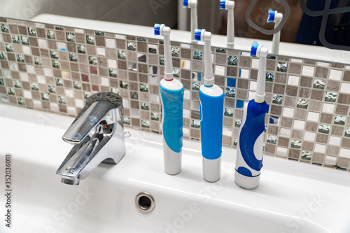 Three electric toothbrushes stand on the washbasin.