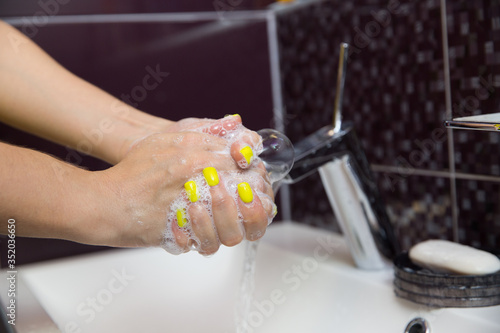 washing hands with antibacterial soap close up on dark background. female washes her hands in the sink under the tap