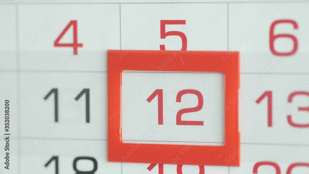 Woman's hand in office changes date at wall calendar. Changes 11 to 12 Woman's hand in office changes date at wall calendar. Changes 11 to 12