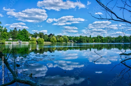 Nice view to the Hundekehlesee in Berlin-Grunewald. The clouds of the summer sky are reflected in the water of the lake.