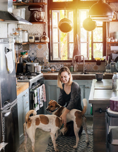 Photography Mature woman cheered by two dogs paying her a friendly visit in a rural house