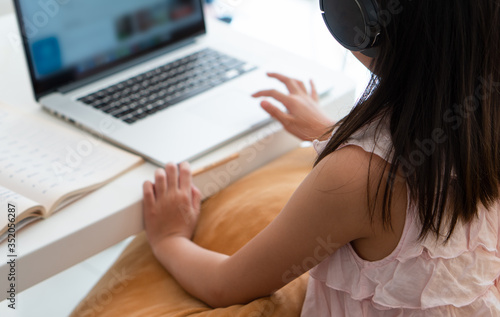 A young asian girl  using computer to leran at home as social distancing protocol during covid-19 or coronavirus pandemic. home schooling concept photo