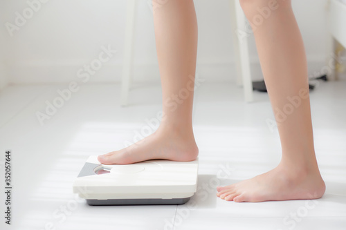 Lifestyle activity leg of woman stand measuring weight scale for diet with barefoot, closeup foot of girl slim weight loss measure for food control and nutrition, healthy care and wellness concept.