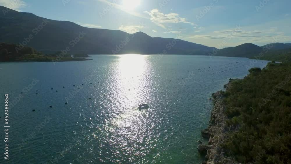 Aerial forward shot of person traveling in boat on sea during sunny day - Ston, Croatia Aerial forward shot of person traveling in boat on sea during sunny day - Ston, Croatia