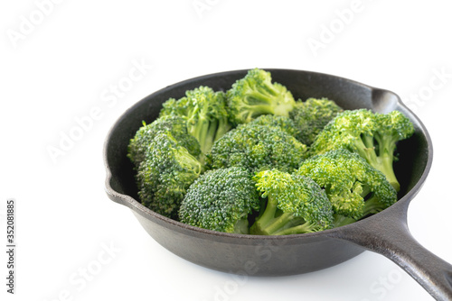 Broccoli florets in a frying pan close up isolated on white background.
