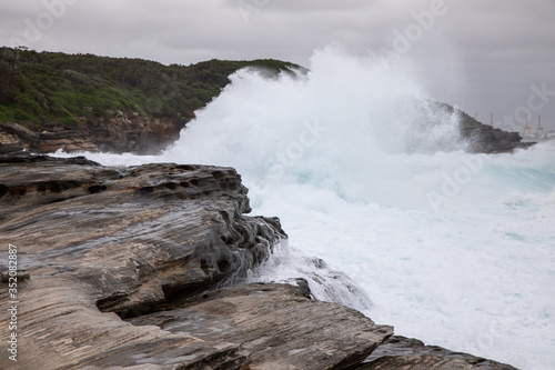 Fototapeta Naklejka Na Ścianę i Meble -  Storm in the ocean. Cloudy sky. Big waves are crashing into the rocks making white foam.