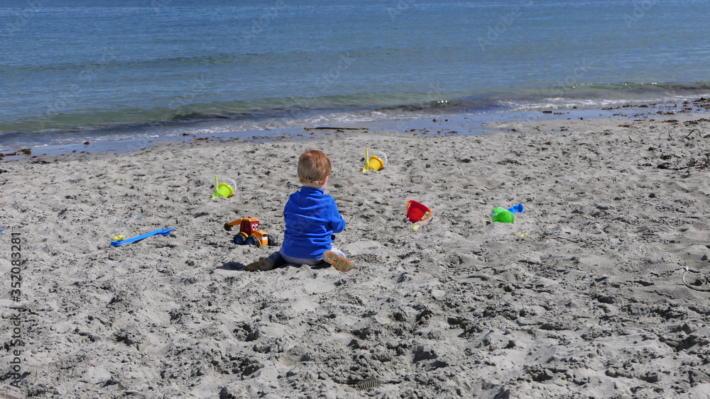 Child playing with bucket and spade while social distancing on a beach in UK Child playing with bucket and spade while social distancing on a beach in UK