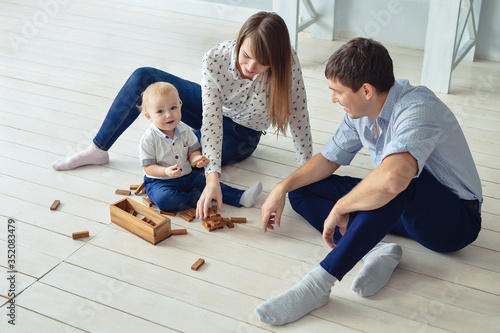 Happy family playing jenga on the floor with their little son