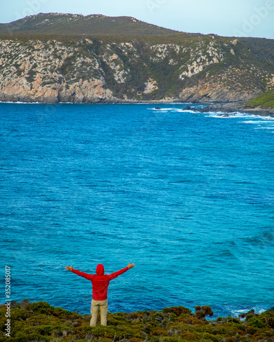 Man in red jacket walking along the beautiful coastline and exploring the cliffs of Fitzgerald River National Park, in Western Australia. The image was taken aerially from a drone. 
