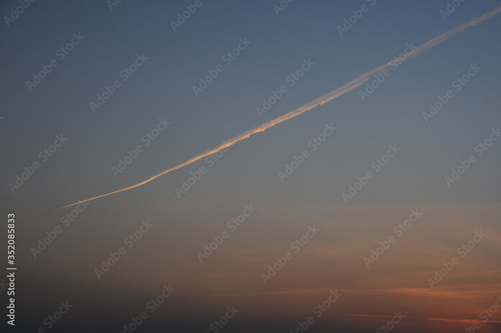 地平線に沈むきれいな夕日と飛行機雲