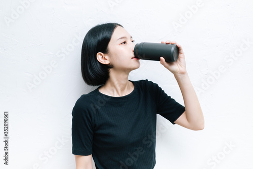 Asian female drink water from black bottle of water.
