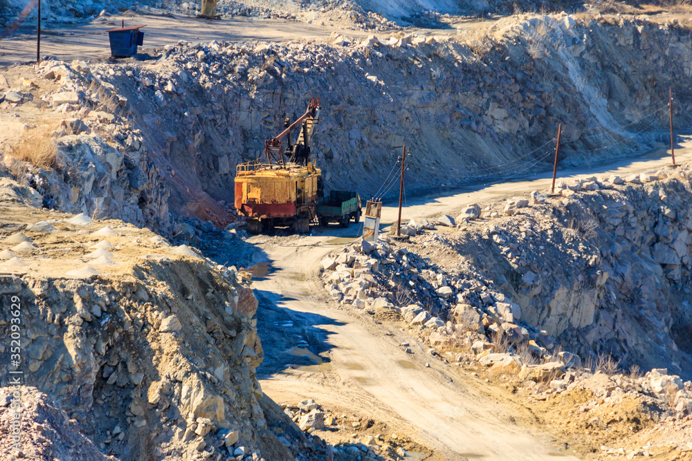 Big yellow excavator working in a granite quarry Big yellow excavator working in a granite quarry