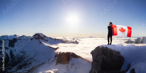 Epic Adventurous Extreme Composite of Girl Holding a Canadian Flag on top of a Mountain. Landscape Background from British Columbia, Canada. Concept: Explore, Hike, Adventure, Lifestyle