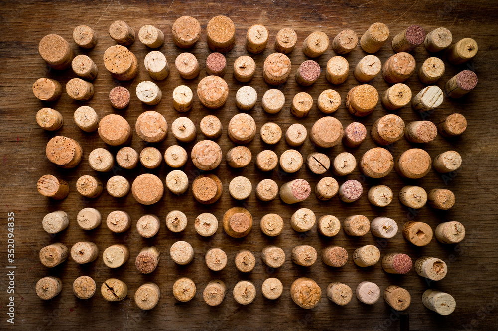Wine corks of different sizes, standing upright on an old wooden surface. Background for liquor.
