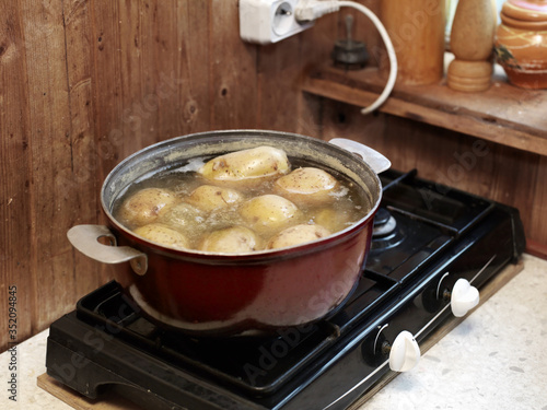 Cooking unpeeled potato on electric stove photo