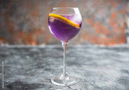 Colorful cocktail with lemon and lavender liqueur in wineglass on the rustic background. Selective focus. Shallow depth of field. 
