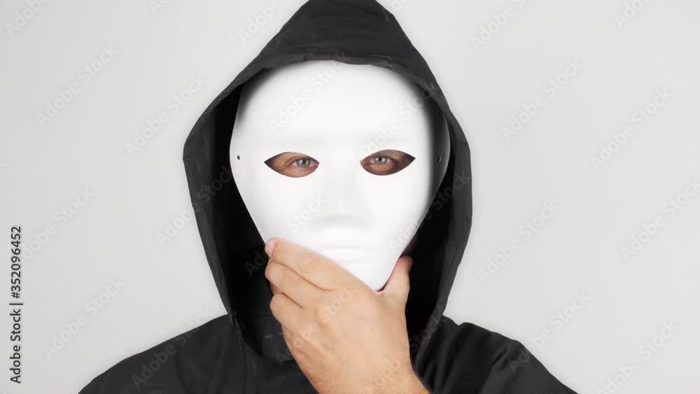 A man in a scary theater mask is looking at the camera. A man takes off his mask and looks into the camera with a crazy look. Maniac. Halloween concept A man in a scary theater mask is looking at the camera. A man takes off his mask and looks into the camera with a crazy look. Maniac. Halloween concept