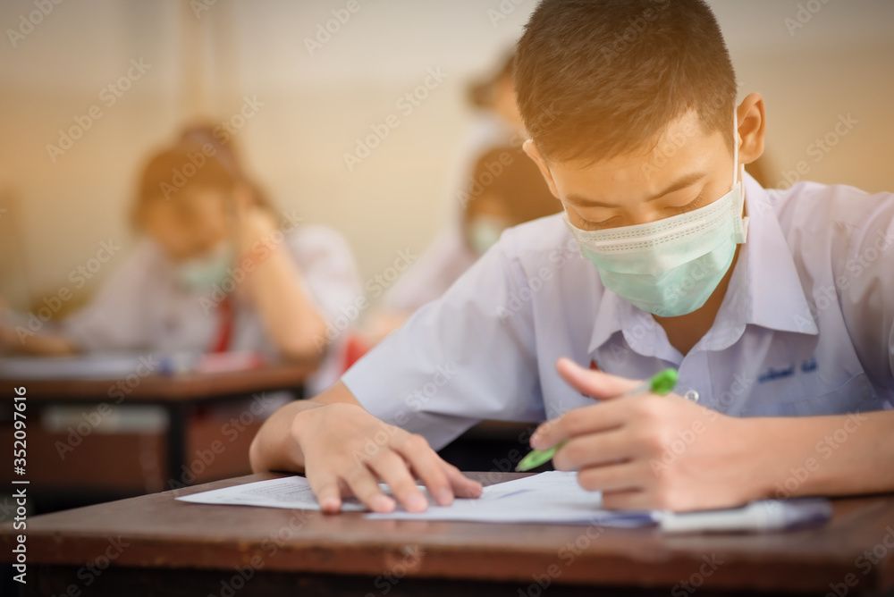 An Asian high school students in a white school uniform wearing a mask to do final exams in the midst of Coronavirus disease 2019 (COVID-19) epidemic and PM 2.5. An Asian high school students in a white school uniform wearing a mask to do final exams in the midst of Coronavirus disease 2019 (COVID-19) epidemic and PM 2.5.