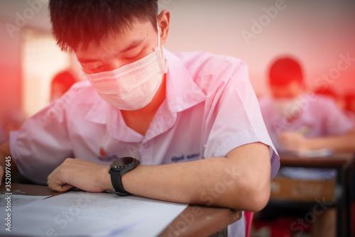 An Asian high school students in a white school uniform wearing a mask to do final exams in the midst of Coronavirus disease 2019 (COVID-19) epidemic and PM 2.5.