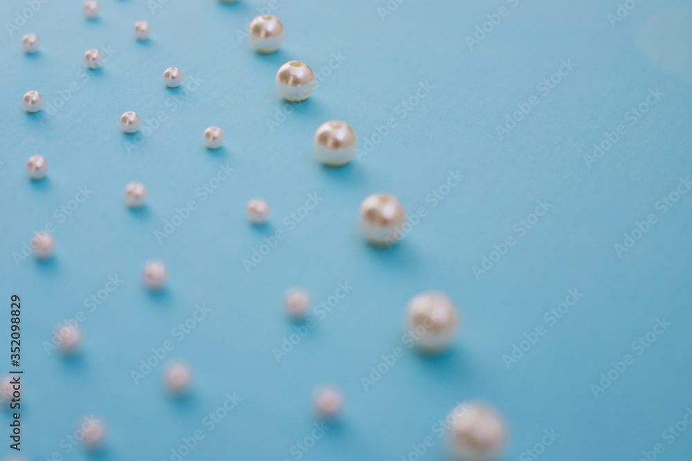 White beads lie in a row on a blue background. Needlework and embroidery. Background and texture. White beads lie in a row on a blue background. Needlework and embroidery. Background and texture.