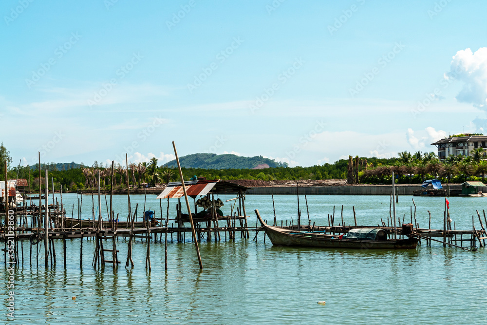 A local fisherman village standing in the water. Traditional colorful asian wooden fishing boats in village. River view with local community under the blue sky in Thailand.
