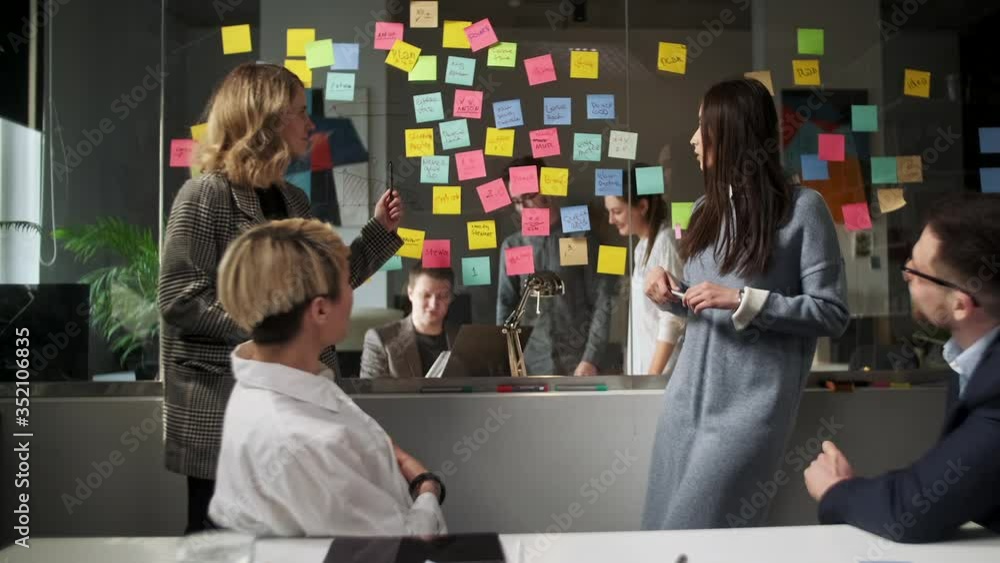 Creative Business Team Brainstorming Ideas Working Together Near Glass Wall With Sticky Notes. Colleagues approve. Business Success Concept Creative Business Team Brainstorming Ideas Working Together Near Glass Wall With Sticky Notes. Colleagues approve. Business Success Concept