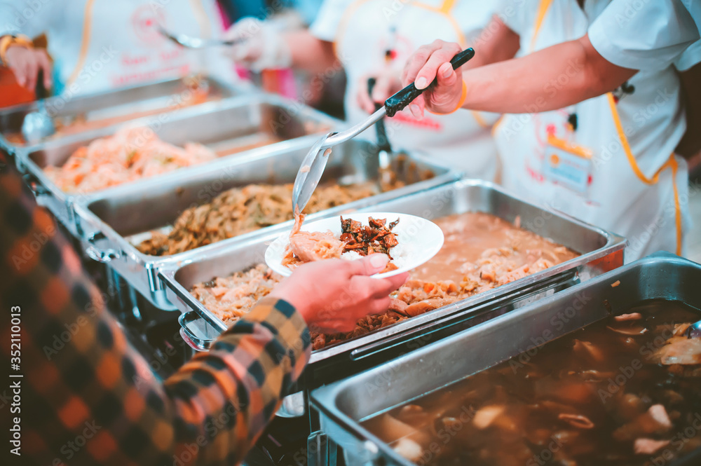 The hand of the wanderer extends to receive food from donations. With volunteers scooping food: the idea of helping with hunger