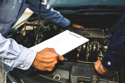 Auto mechanic using checklist for car engine systems after fixed. concepts of car insurance support and services.