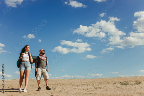 Tourism, destination and travel. Group of tourists with backpacks traveling through desert. Trekking, hiking, active lifestyle and touristic equipment