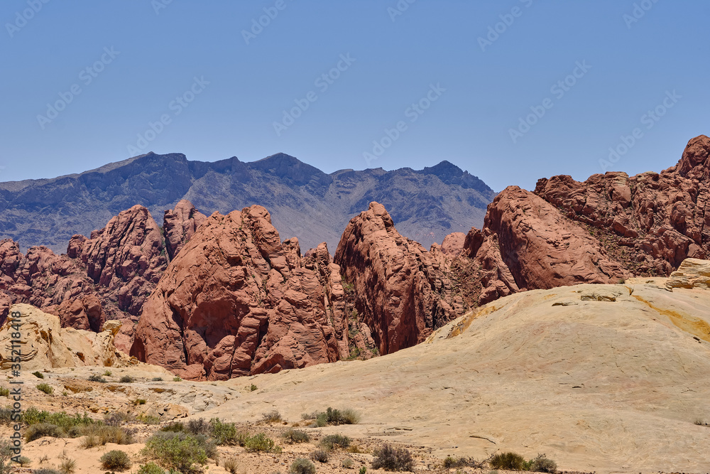 Fototapeta premium Water and weather erosion create patterns in the foreground rocks with the Red Aztec Sandstone in the background