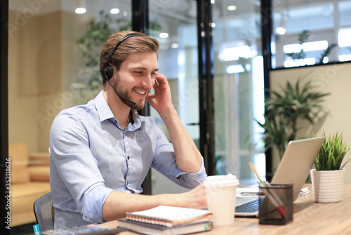 Fotografie Smiling friendly handsome young male call centre operator.
