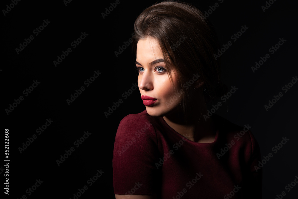 Portrait of attractive blue-eyed young woman over black background. Amazing girl with perfect makeup wearing elegant deep red dress. Beauty and fashion Portrait of attractive blue-eyed young woman over black background. Amazing girl with perfect makeup wearing elegant deep red dress. Beauty and fashion
