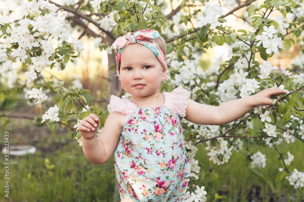 Cute baby girl on a background of white blossoms of an apple tree Cute baby girl on a background of white blossoms of an apple tree