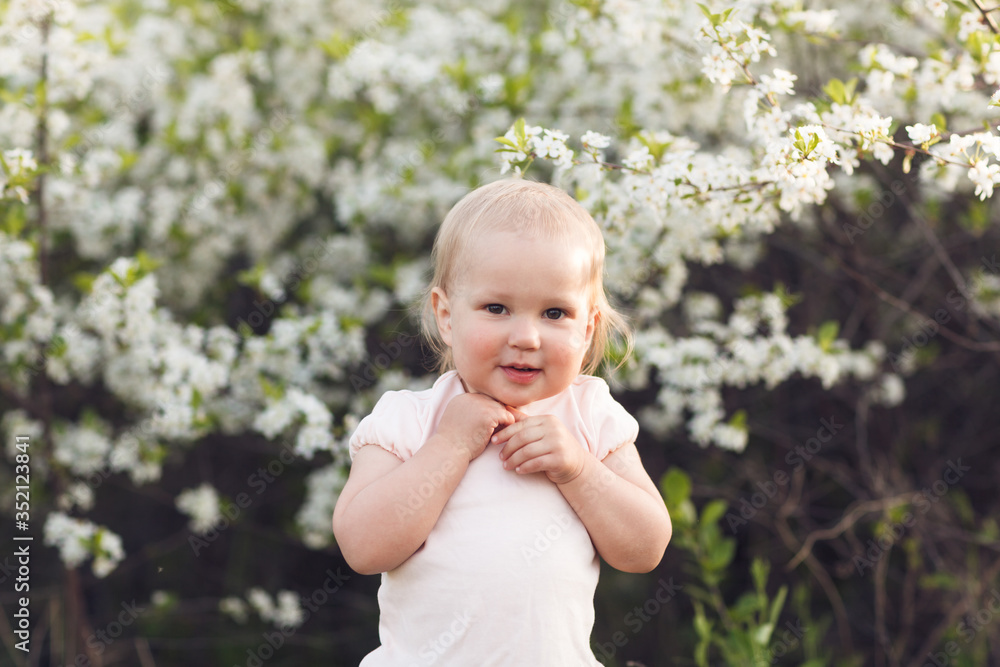 Cute baby girl on a background of white blossoms of an apple tree Cute baby girl on a background of white blossoms of an apple tree
