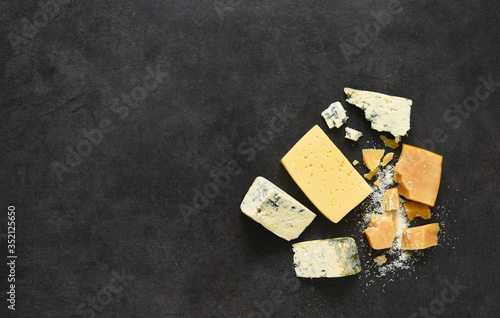 Cheese set: brie, blue cheese, parmesan on a black concrete background. View from above.