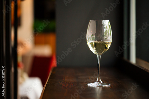 Elegant glass of white wine on wooden bar counter