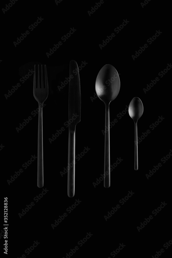 still life of black cutlery on black background, fork, knife, spoon, teaspoon 