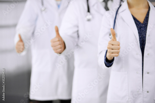 Doctors standing as a team with thumbs up in clinic and ready to help patients. Medical help, insurance and medicine concept