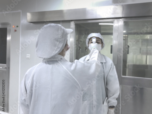 blur image of factory worker standing checking temperature before go to working area. Clean room..blurred background, Concept Virus protection.