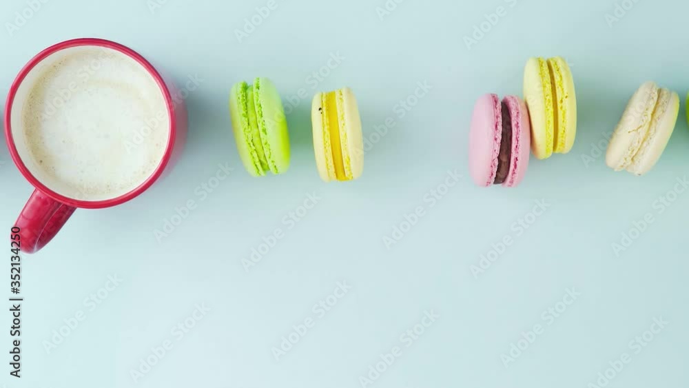 Macaroons or macaron on pastel blue surface with coffee in red cup. Macaroons or macaron on pastel blue surface with coffee in red cup.