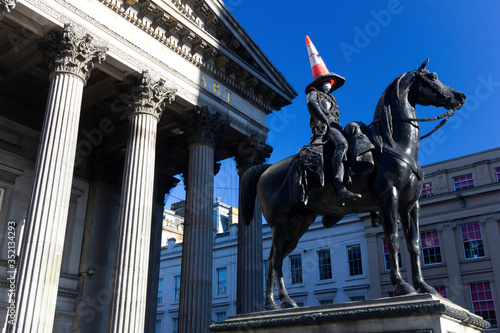 The Duke of Wellington Sculpture in Glasgow city centre with a cone on his head and a personal protective equipment face mask on his face during the 2020 Corona Virus lockdown in Scotland.  